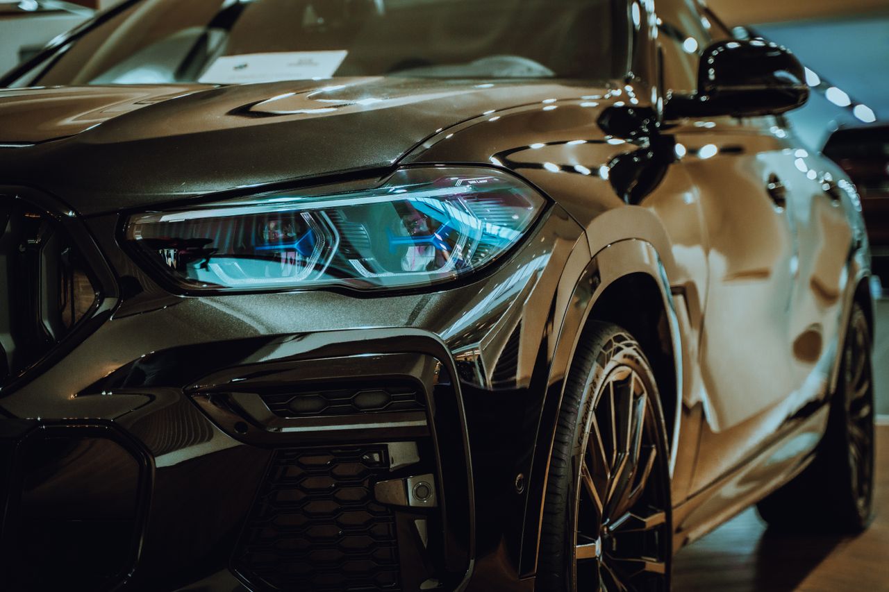 Close-up of a sleek, luxurious black car with stunning reflections in an indoor parking lot.