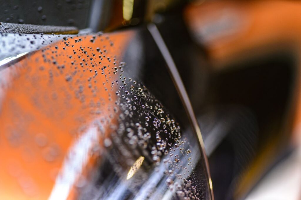 pexels photo 248395 Close-up view of water droplets on a glossy car surface with a blurred background.