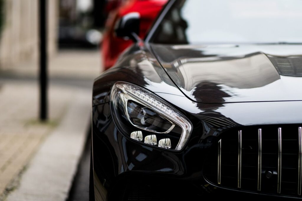 pexels-photo-6152798-6152798 Close-up of a sleek black luxury car with reflections on the streets of London.